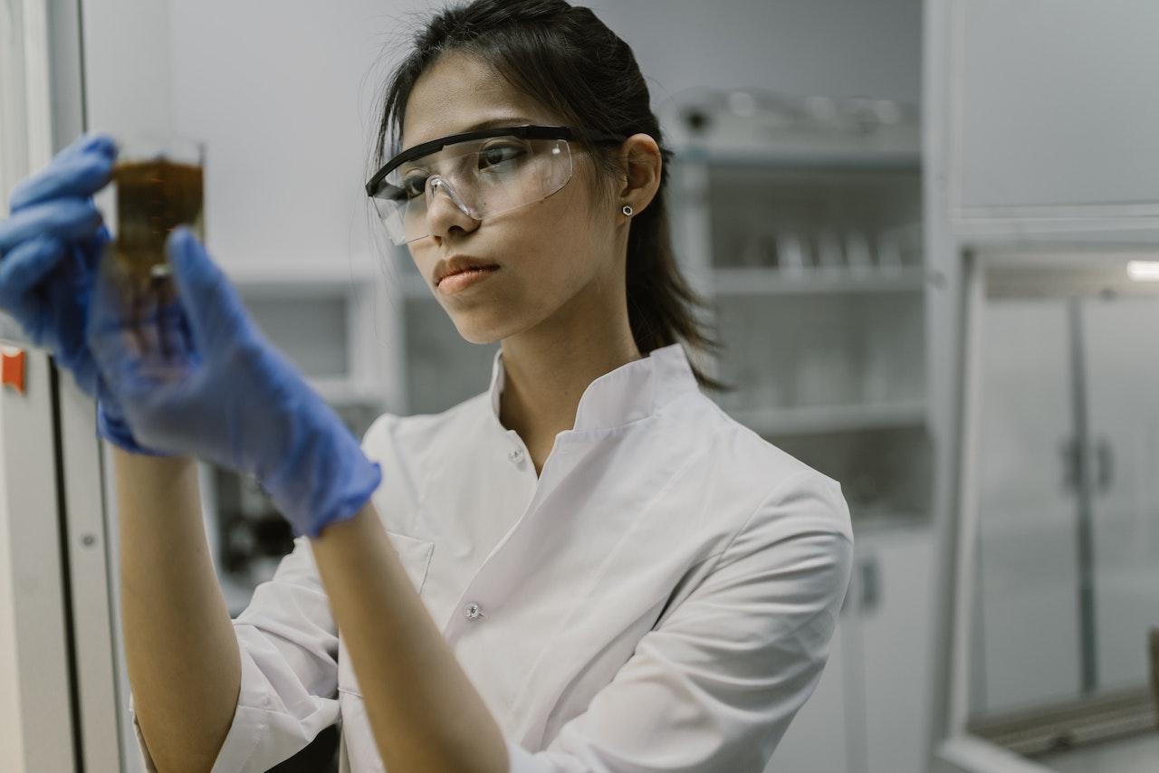 A woman holding a beaker with liquid in it