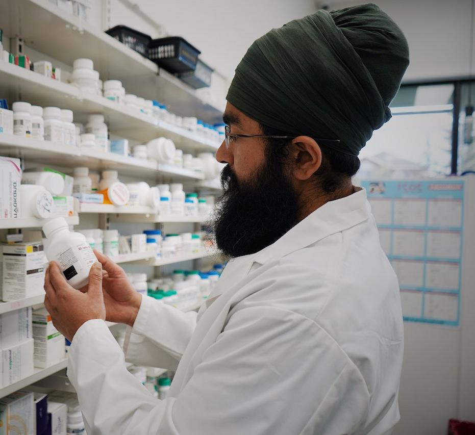 Pharmacist in front of Shelves with Medicines