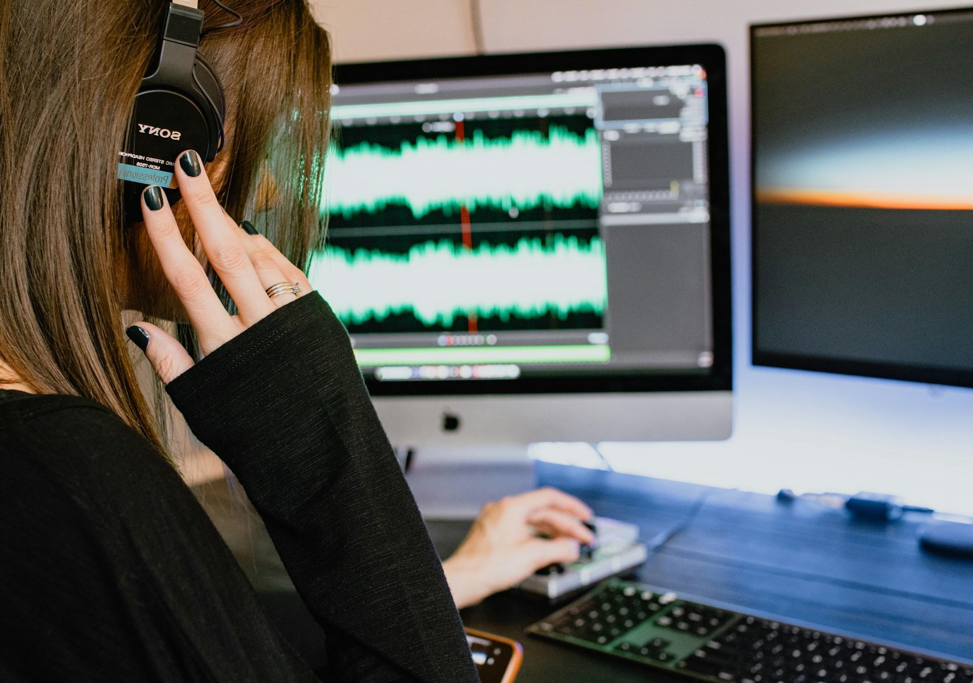 Woman with headphones working on music on a computer